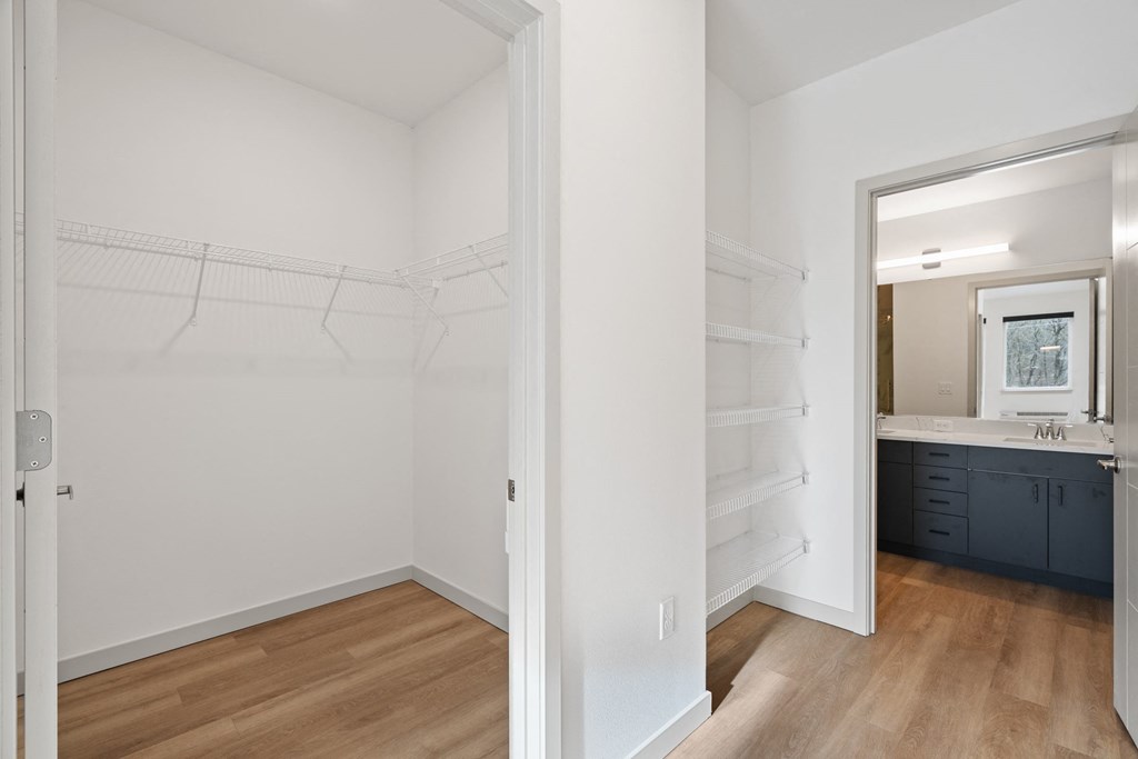 a bedroom with a closet and a bathroom with a sink and a mirror