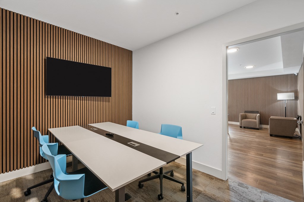 a conference room with a table and chairs and a tv on the wall