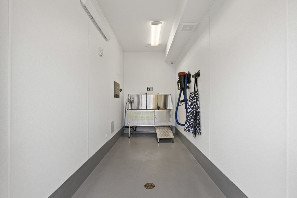 a long white hallway with white walls and a metal cart with hoses in it