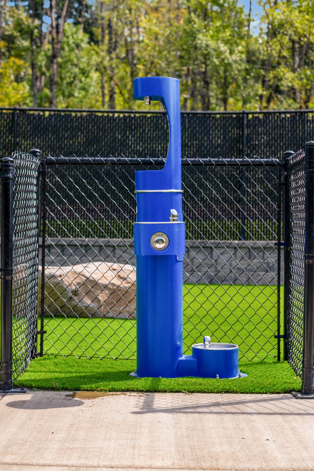 a blue water fountain in front of a fence