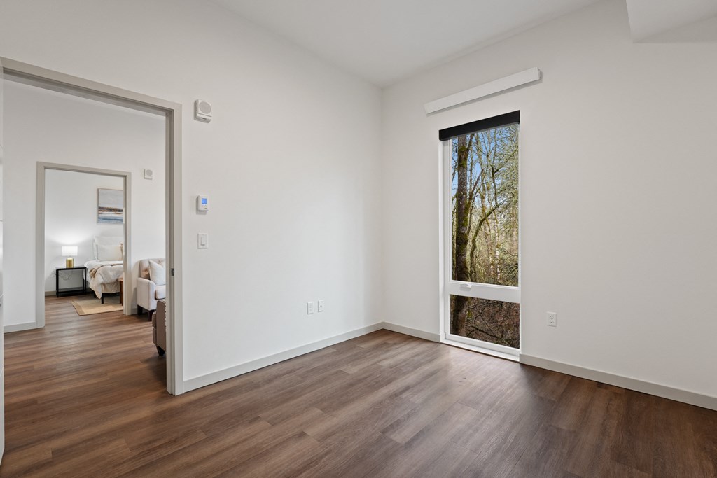 a living room with white walls and a large window and wooden floors