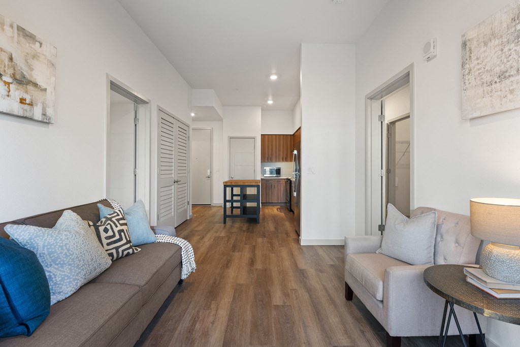 a living room with a couch and a table and a kitchen in the distance