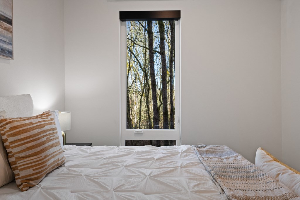 a bedroom with a bed and a window with trees