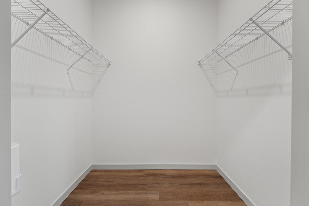 an empty room with white walls and wooden floors and wire shelves on the wall