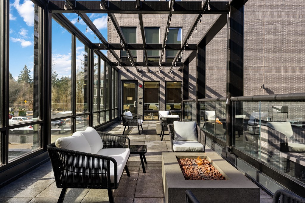 a patio with chairs and a coffee table and large windows