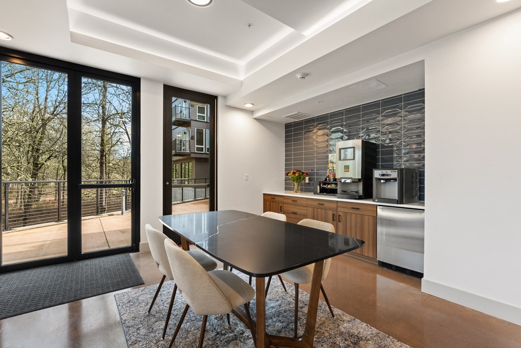 a dining room with a black table and chairs and a kitchen with glass doors