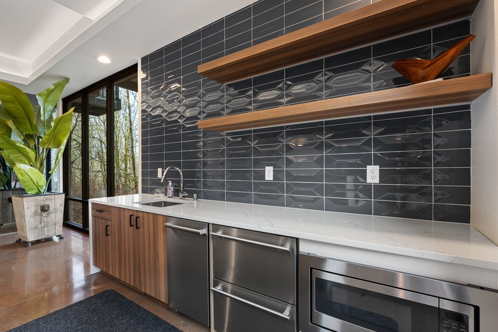 a kitchen with stainless steel appliances and a black tile backsplash