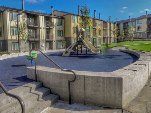 A playground with a slide and a concrete structure in the foreground.
