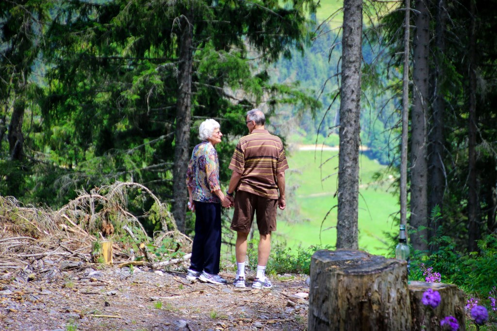 Two people are standing on a dirt path in the woods.