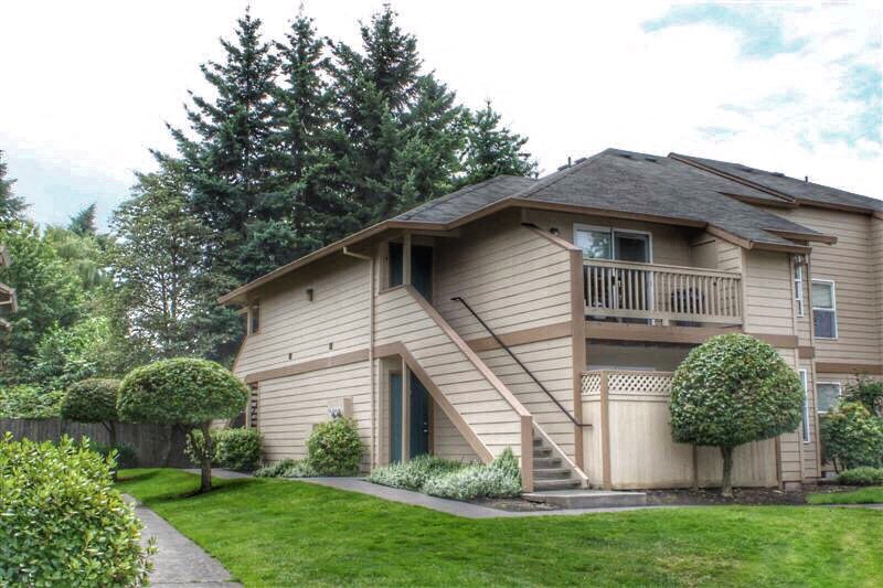 a tan house with a balcony and a lawn