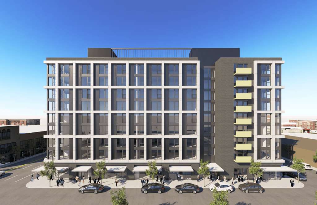 A modern building with a glass facade and a parking lot in front.