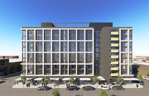A modern building with a glass facade and a parking lot in front.