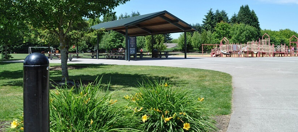 A black post is in the foreground of a park with a playground in the background.