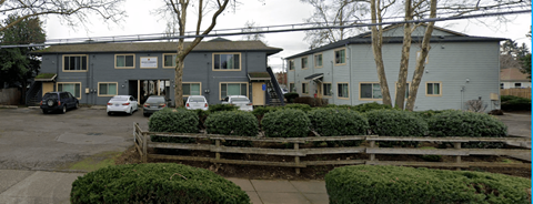 A grey building with a white car parked in front.