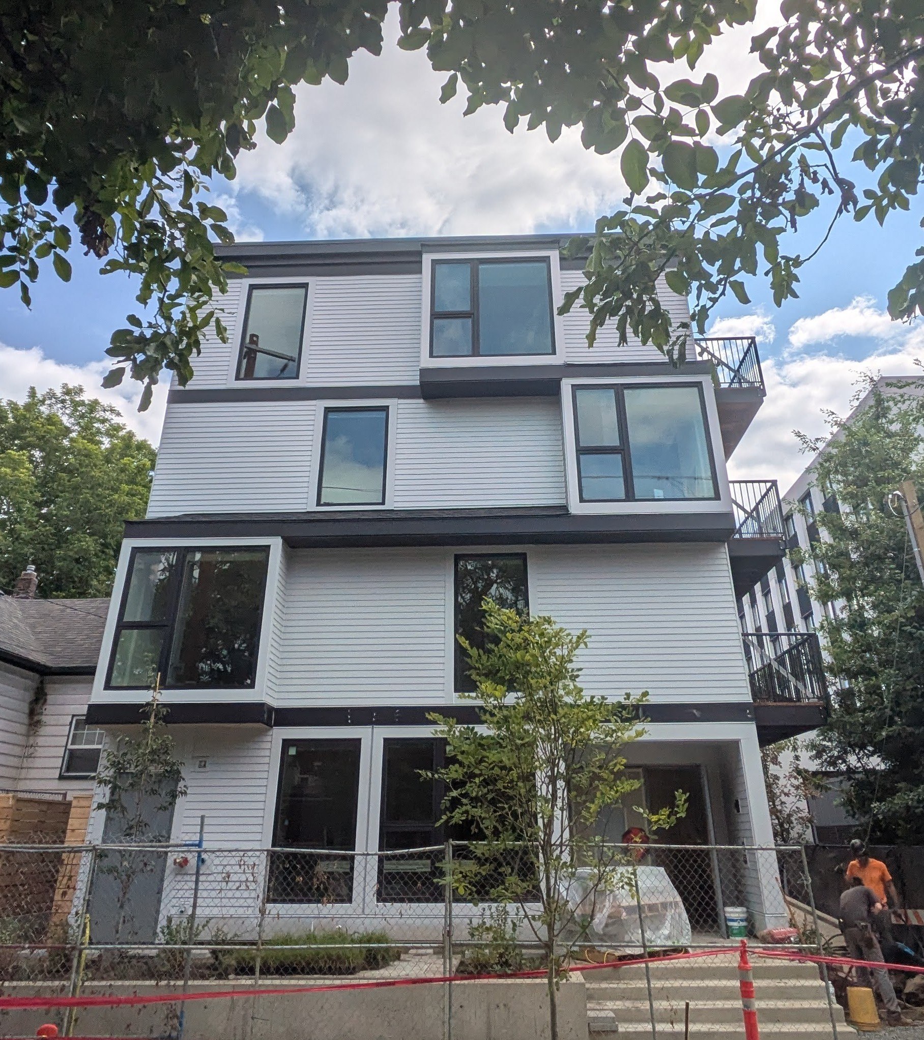 A modern house under construction with white siding and large windows.