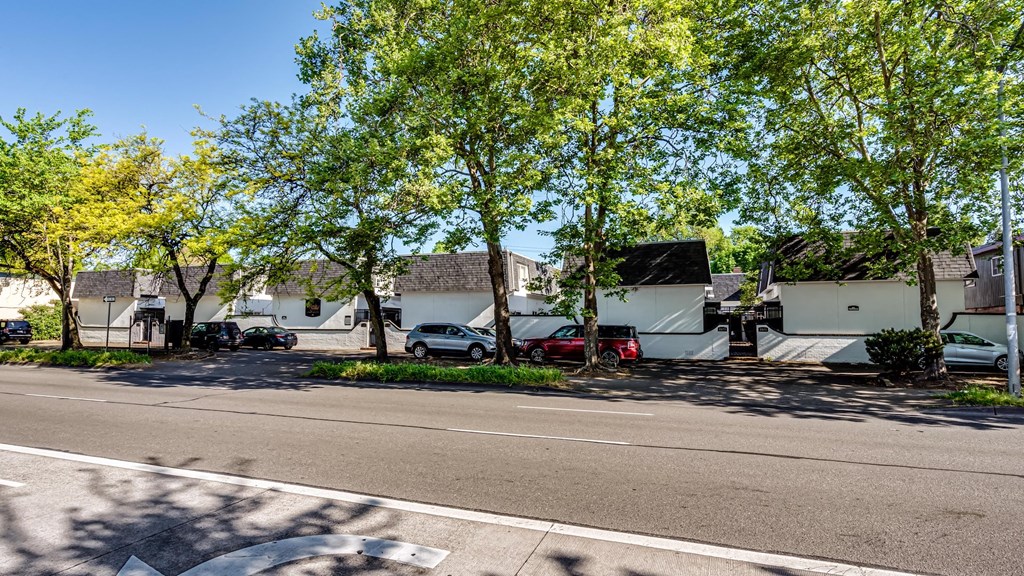 a street with houses and trees and cars parked in front of them