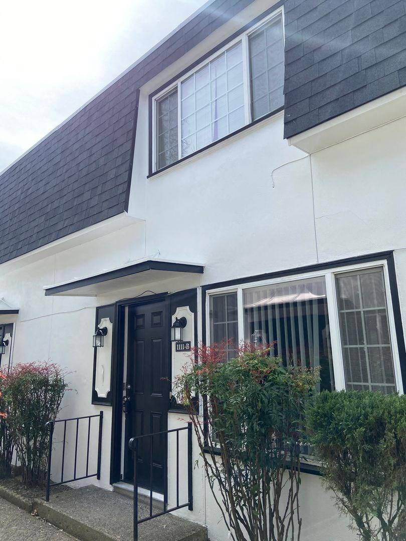 the front of a white house with a black door