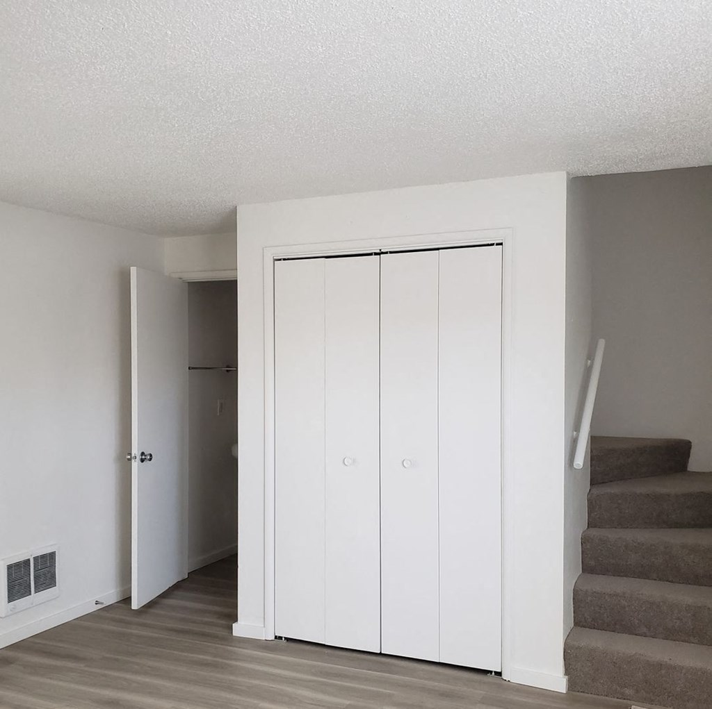 an empty room with stairs and a white closet
