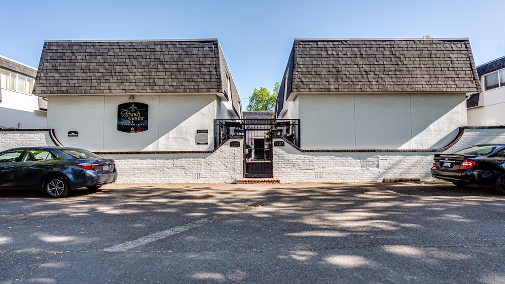 the front of a white building with cars parked in front of it