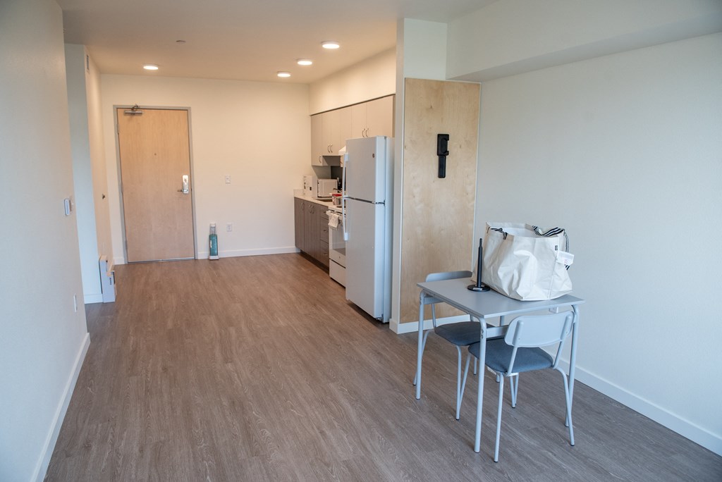 a view of a kitchen and a small table in a room with a refrigerator