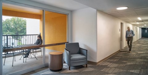 a man walking down a hallway in a room with a table and chairs