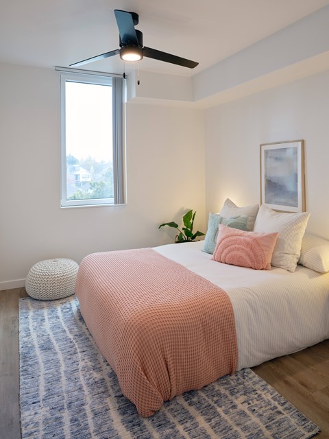 A bedroom with a bed, a ceiling fan, and a window.
