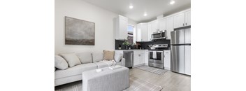 a living room with a couch and a kitchen with stainless steel appliances