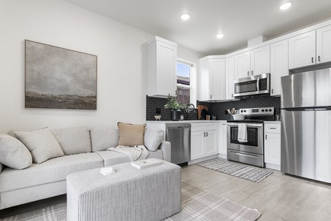 a living room with a couch and a kitchen with stainless steel appliances