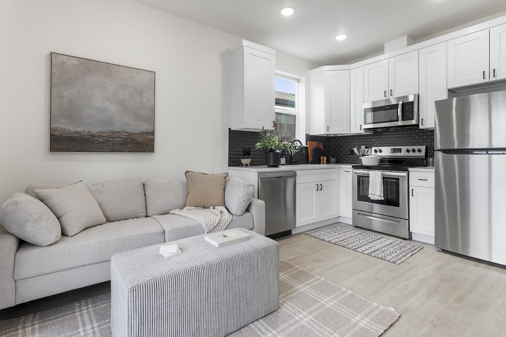a living room with a couch and a kitchen with stainless steel appliances