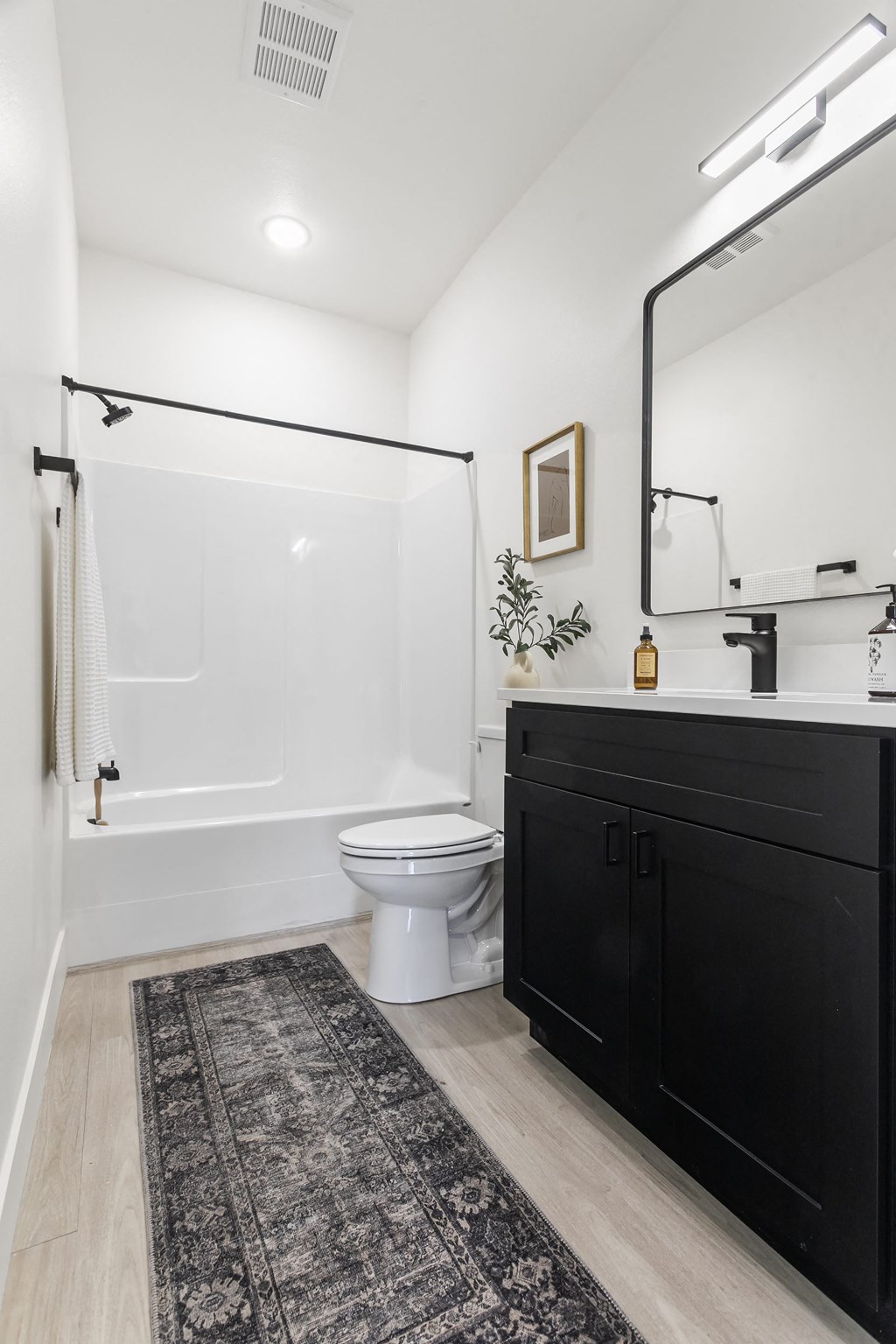 a bathroom with a shower and a toilet and a black vanity