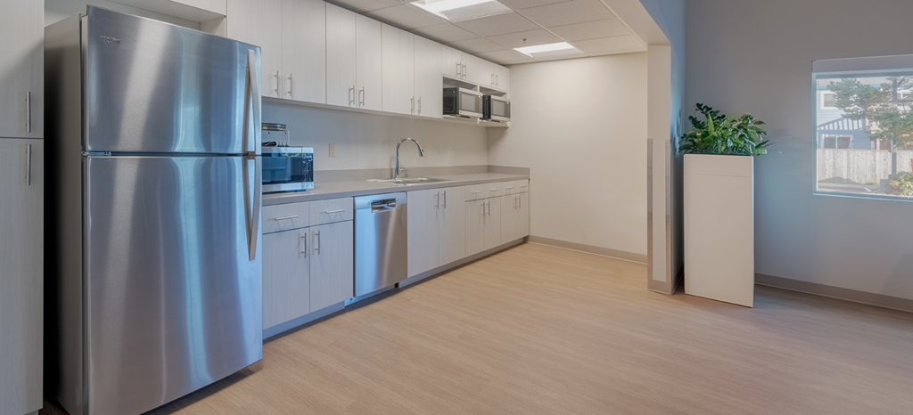 A kitchen with a stainless steel refrigerator and white cabinets.