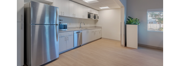 A kitchen with a stainless steel refrigerator and white cabinets.