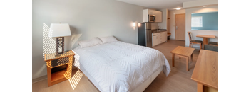 A bedroom with a bed, a table, and a chair.