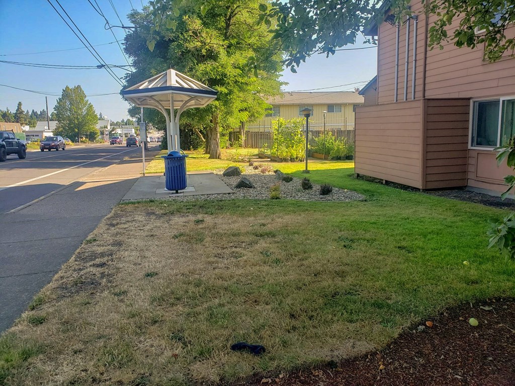 a blue trash can sitting on the side of a street