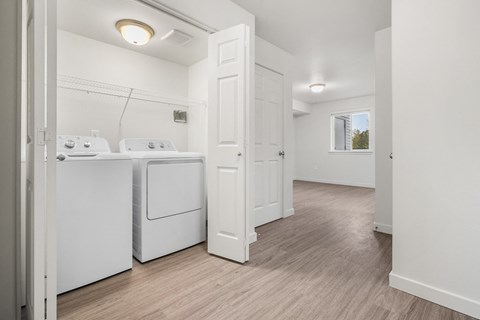 A white bathroom with a wooden floor and a window.