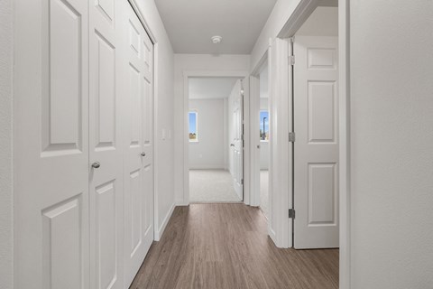 A long hallway with white doors and wood floors.