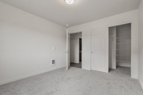 A white room with a carpeted floor and a doorway leading to another room.