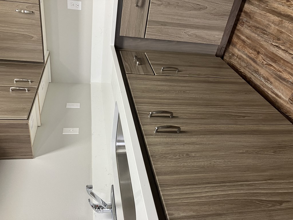 a kitchen with wooden cabinets and drawers and a white wall
