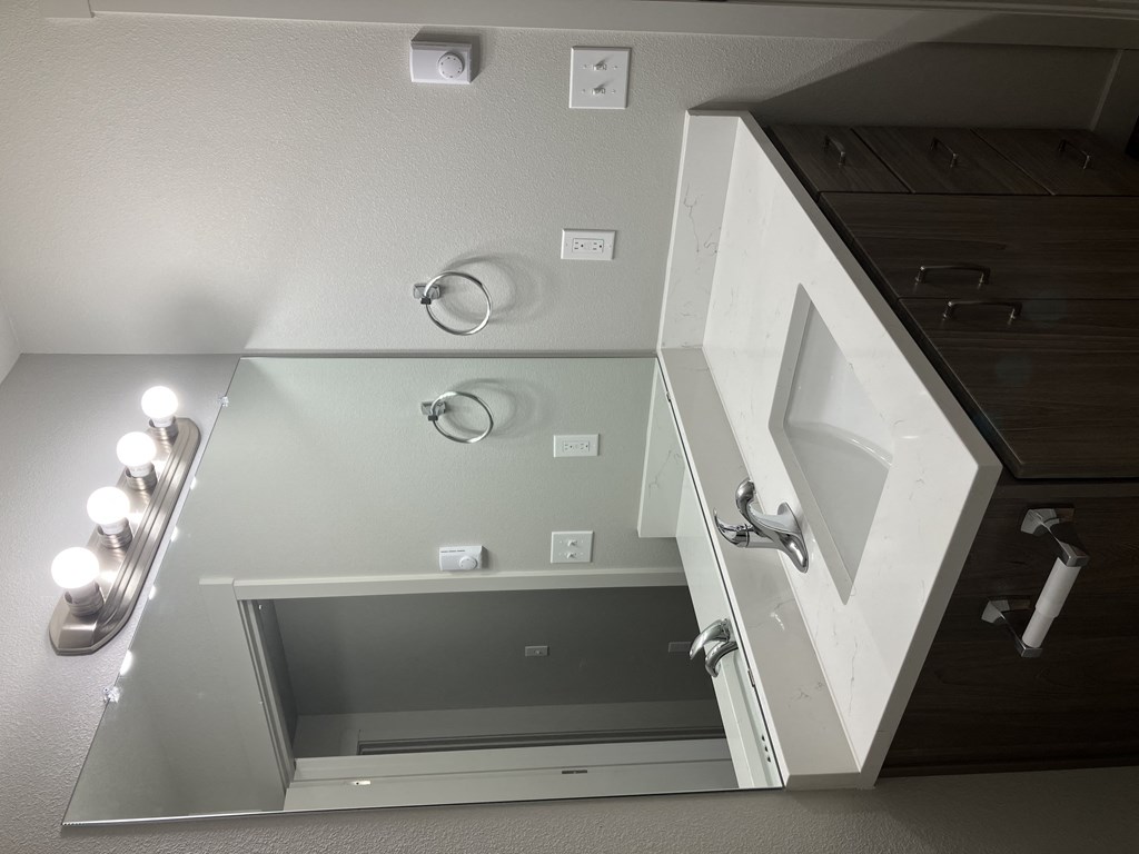 the bathroom has a large mirror and a cabinet with a sink