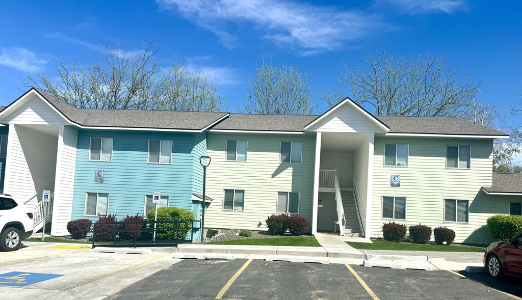 A blue and white building with a parking lot in front.