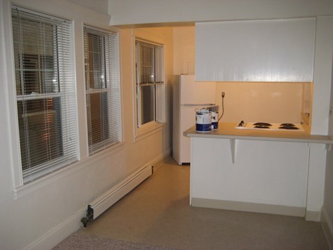 A kitchen with white cabinets and a refrigerator.