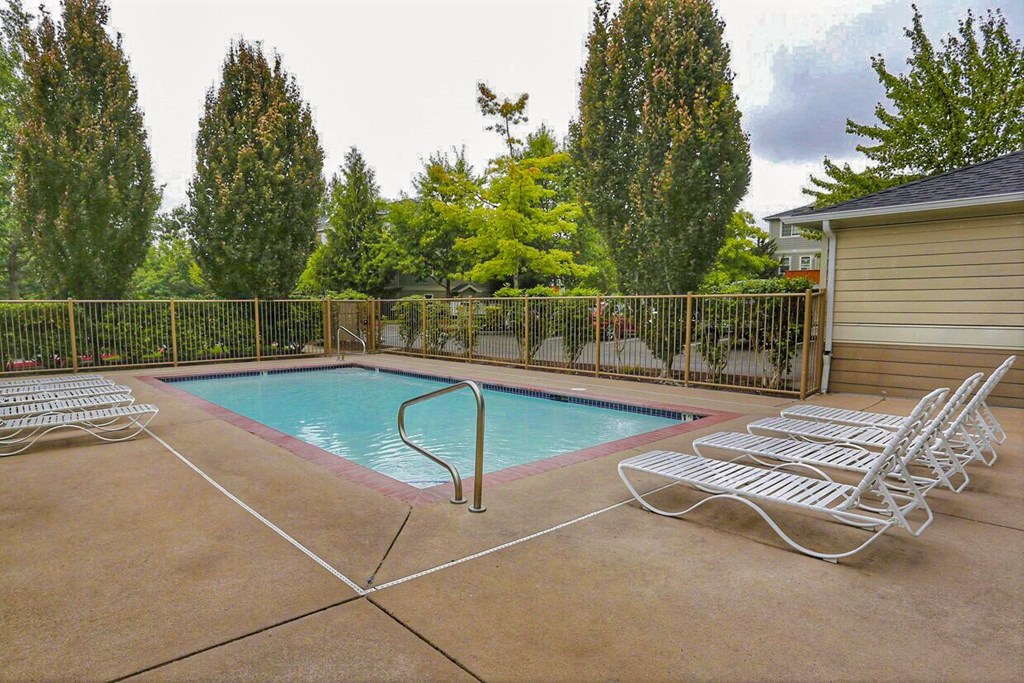a swimming pool in the backyard of a house with lounge chairs