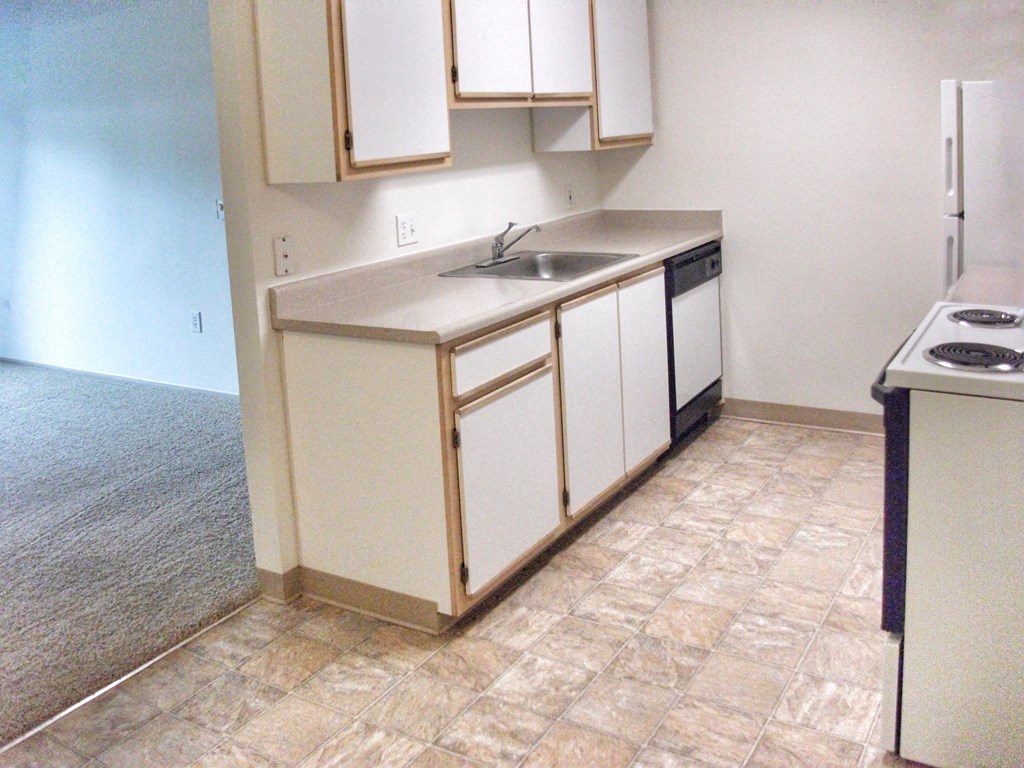 an empty kitchen with white cabinets and a sink