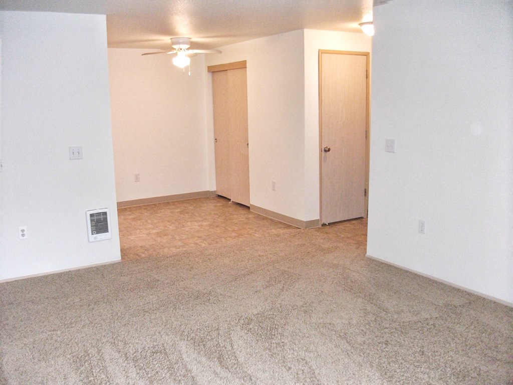 an empty living room with carpet and white walls