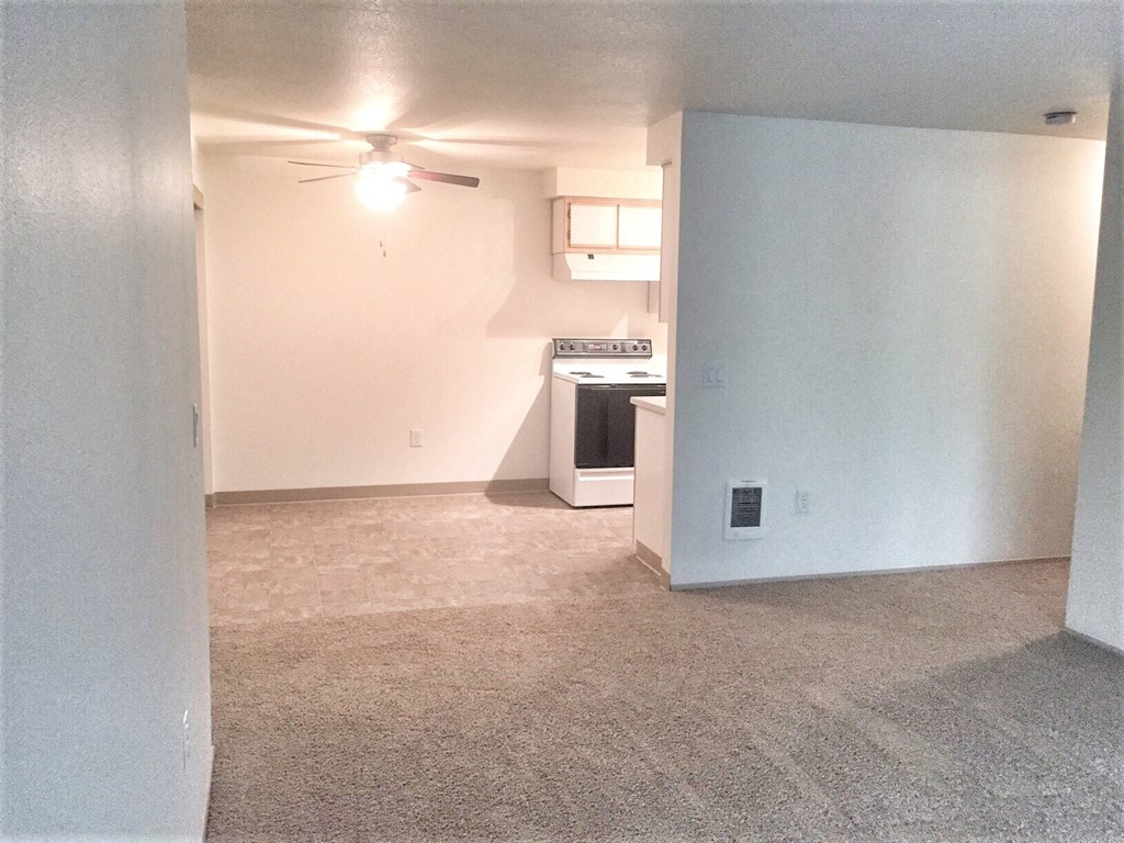an empty living room and kitchen with a ceiling fan