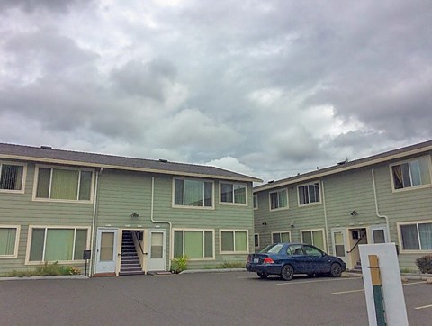 A car is parked in front of a building with a grey sky in the background.