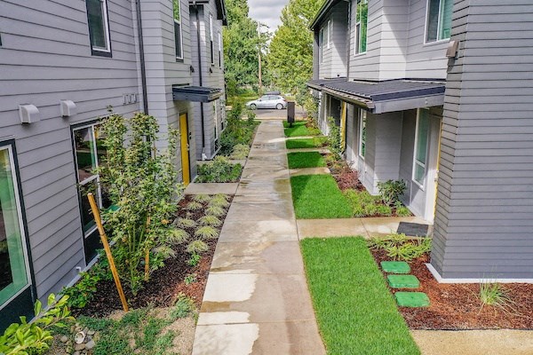 a sidewalk between two houses with a car in the distance