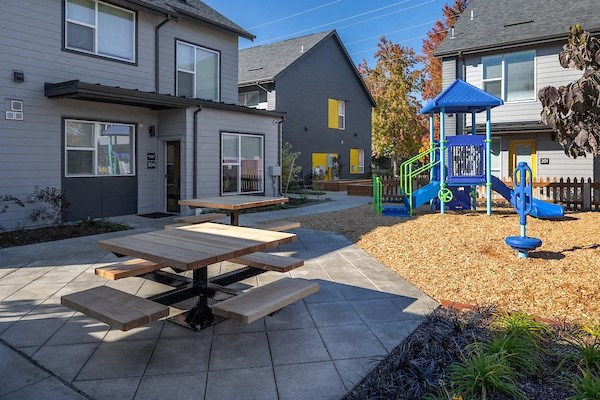 a playground and picnic table in front of a house