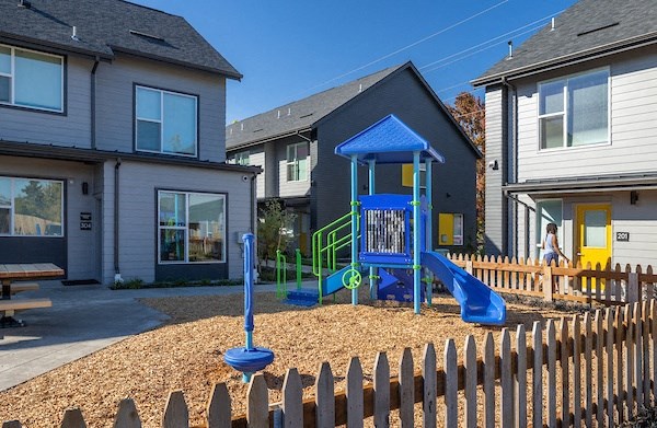 a playground in front of a house with a blue swing set