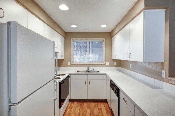 a white kitchen with white cabinets and a refrigerator